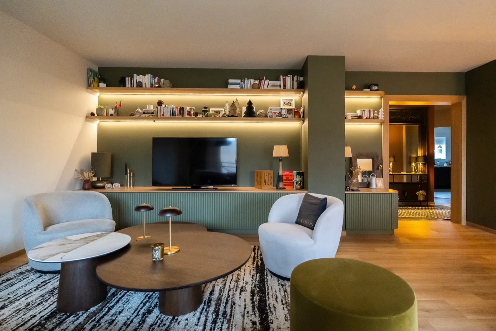 Salon aux murs vert sauge, bibliothèque éclairée